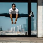 Man performing a split jump on concrete, showcasing fitness and agility.
